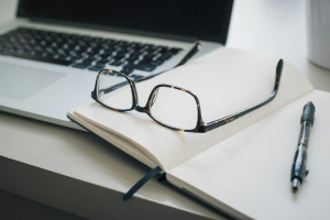 Libreta, lentes y pluma